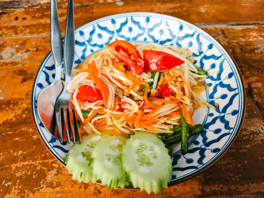 A plate of noodles with vegetables and cucumbers